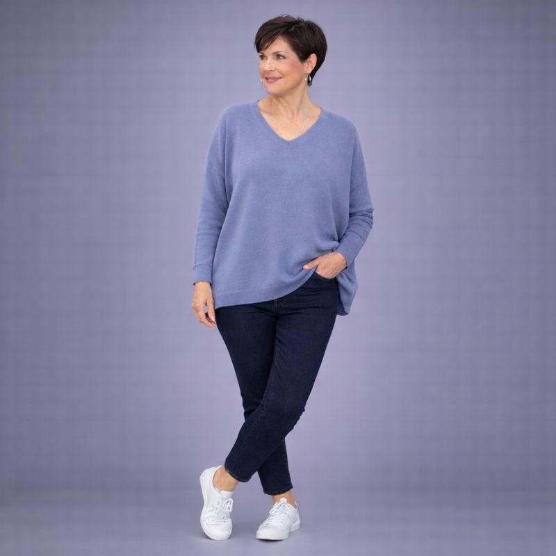 Cozy blue sweater featuring a V-neck design, paired with dark pants and white sneakers.